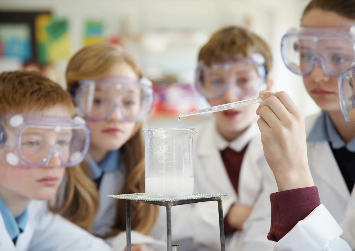 kids performing a science experiment with a beaker and dropper